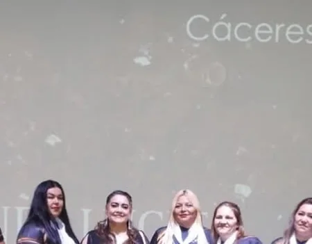 Cinco integrantes del Área Andalucita en un escenario, con el apellido Cáceres proyectado detrás
